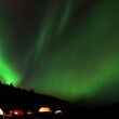 The northern lights shine brilliant green above an exploration camp.