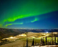 Wide band of brilliant green northern lights over a gold mine in the Yukon.