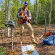 Geologist with handheld drill collects soil sample at copper project in Alaska.