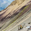 Technicians constructing a drill pad on the side of a slope.