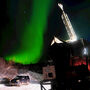 A green streak of the aurora over a drill rig set up in winter.