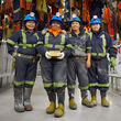 Four women from Nunavut in mining apparel with a large bar of gold.