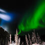 A band of green aurora over a drill testing for gold on an Alaska winter night.