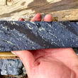 “Zebra-striped” drill core with bands of metallic striations, black rock.
