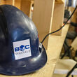 A blue hardhat with the BMC Minerals logo sits on shelf at the ABM Mine camp.
