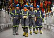 Four women from Nunavut in mining apparel with a large bar of gold.