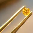 A pair of tweezers holding a fancy yellow diamond from the Naujaat project.
