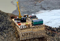 A drill rig set on a beefy drill pad in a rugged Alaska mountain setting.