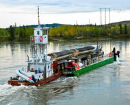 Barge carries semi with two trailers of copper concentrate across Yukon River.