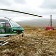 Two workers walk from a helicopter to drill at the Pebble project in Alaska.