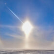 A colorful sundog encircles the sun over a frozen plain in Canada’s North.