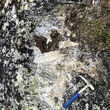 Hand pick laid across an exposed outcrop of a lithium-bearing pegmatite.