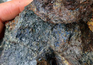 A hand-sized rock sample with extensive blue and gold-copper mineralization.