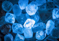 A closeup of rough diamonds lit with a soft blue light.