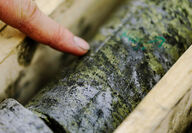 Finger points at drill core with high-grade copper mineralization.