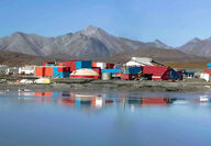 The red, white, and blue buildings at Red Dog reflect off tailings pond water.