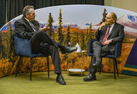 Alaska governor and energy analyst sitting in front of Alaska landscape photo.