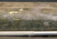 A section of drill core with bands of metallic gold-colored mineralization.