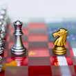 Chess board underlain by China and US flags representing strategic positioning.