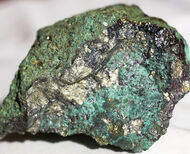 Softball-sized silver-, gold-colored rock stained green with copper oxides.