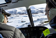 Pilots flying over a drill rig on a snowy field in Southwest Alaska.
