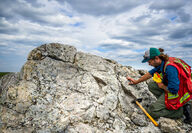 Li-FT geologist examines a large, exposed outcrop at Yellowknife Lithium.