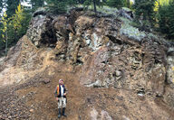 Geologist stands in front of mineralized rock face in Canada’s Yukon.