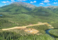 Alaska mineral exploration camp and airstrip along a river and base of mountain.