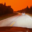 Photo taken through car windshield by evacuee in line of cars under red sky.
