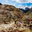 Geologists in safety gear traverse heavily mineralized rocks.