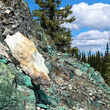A rocky hillside full of greenish rocks that make up copper mineralization.