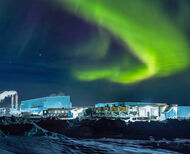 An arc of green northern lights over industrial building in Canada’s North.