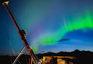Bands of green aurora over a drill testing for nickel in Alaska.