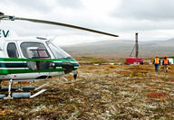 Two workers walk from a helicopter to drill at the Pebble project in Alaska.