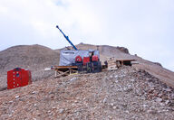A drill atop a rocky ridge tests the Johnson Tract gold project in Alaska.