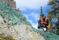 Gladiator Metals geologist inspecting copper mineralization on slope.