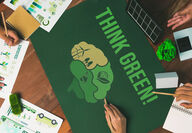 People gathered around a table covered with a mat that says, “THINK GREEN!”
