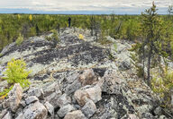 A Li-FT geologist stands atop a large outcrop of white pegmatite in NWT.