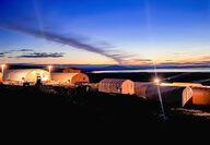 Lights illuminate Quonset tents at dusk on Alaska’s west coast.