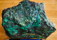 A rough eight-inch rock sample stained green from copper oxides.