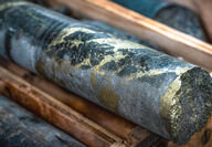 Bands of gold-colored copper mineralization ribbon dark grey drill core.