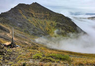A drill tests a rich metals deposit from a mountain saddle above the clouds.