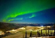 Wide band of brilliant green northern lights over a gold mine in the Yukon.