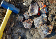 Rock hammer provides context for copper enriched rock samples.