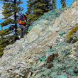 A geologist examines a slope riddled with copper mineralization.