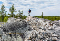A geologist standing atop a large white outcropping pegmatite in NWT.
