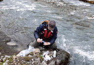 Technician collecting water samples from stream on Iskut property in Canada.