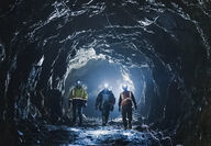 Three workers surrounded by a blue light in an underground mine at Premier.