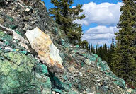 A rocky hillside full of greenish rocks that make up copper mineralization.