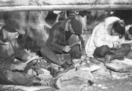 Alaska Native men carving ivory with various tools.